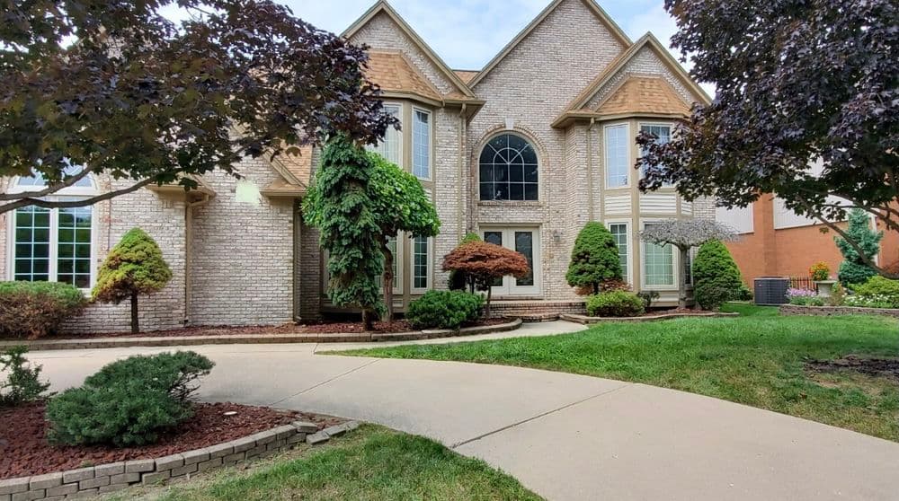 Elegant brick home with arched windows, well-maintained landscaping, and a paved driveway.