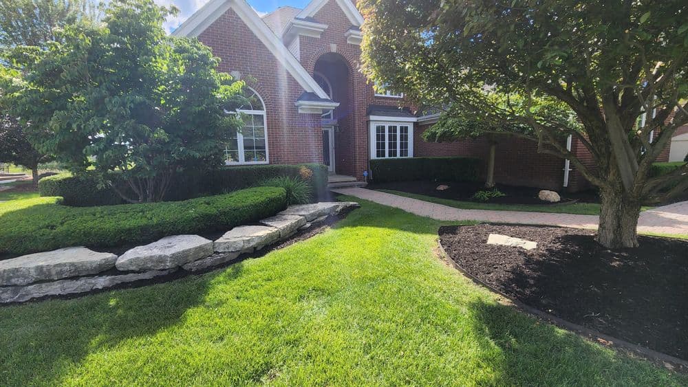 Brick home exterior with landscaped yard, stone path, and vibrant green lawn.