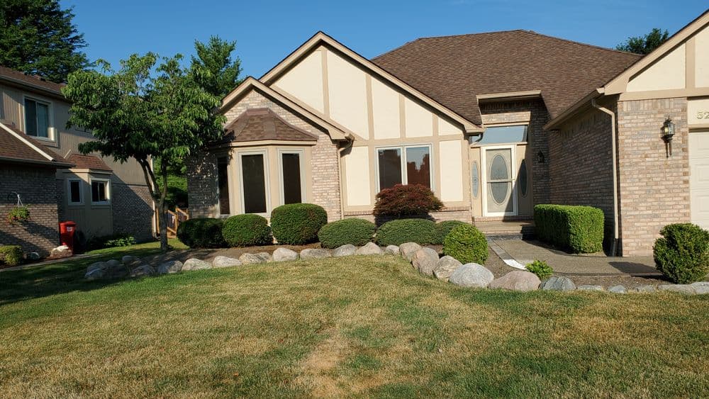 Charming suburban home with brick exterior, landscaped yard, and clear blue sky.